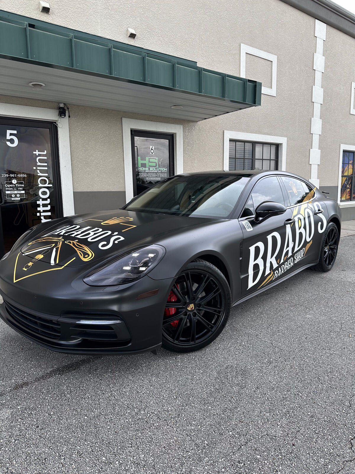 Real install — Porsche Panamera wrapped in Avery Satin Black for Brabo's Barbershop by Brittoprint, Fort Myers. Photographed in-house. © 2026 Brittoprint.